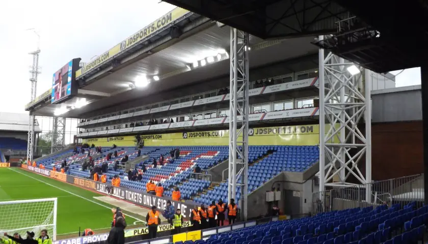 Puste trybuny stadionu Crystal Palace, z widokiem na murawę i tablicę wyników.