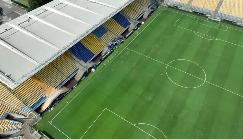 Puste trybuny stadionu Ennio Tardini, z zieloną murawą i białymi liniami boiska.