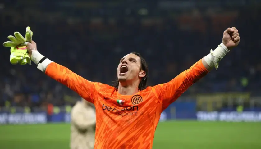 Bramkarz Yann Sommer w pomarańczowej koszulce z podniesionymi rękami świętuje zwycięstwo.