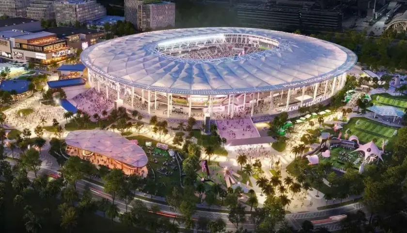 Nowoczesny **Inter Miami stadium** z rozsuwanym dachem, otoczony parkiem z boiskami i atrakcjami, nocą.