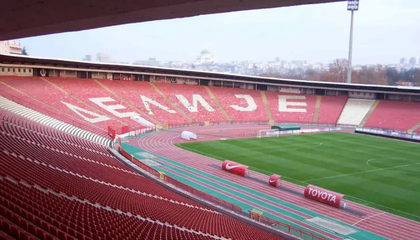 Puste trybuny stadionu Crvena Zvezda czekają na kibiców. Na tle miasta widać charakterystyczną kopułę.