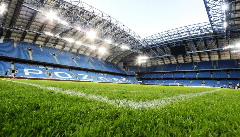 Zielona murawa i niebieskie trybuny stadionu Lecha Poznań, gotowe na kolejny mecz.