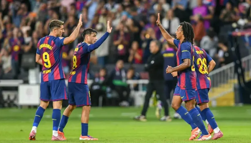 Piłkarze FC Barcelona świętują zwycięstwo w rozgrywkach. Lewandowski, Pedri i Koundé podnoszą ręce w geście radości na boisku.