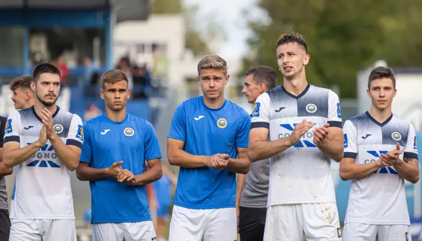 Pięciu młodych piłkarzy Hutnika Kraków w strojach klubowych stoi w rzędzie, klaszcząc.