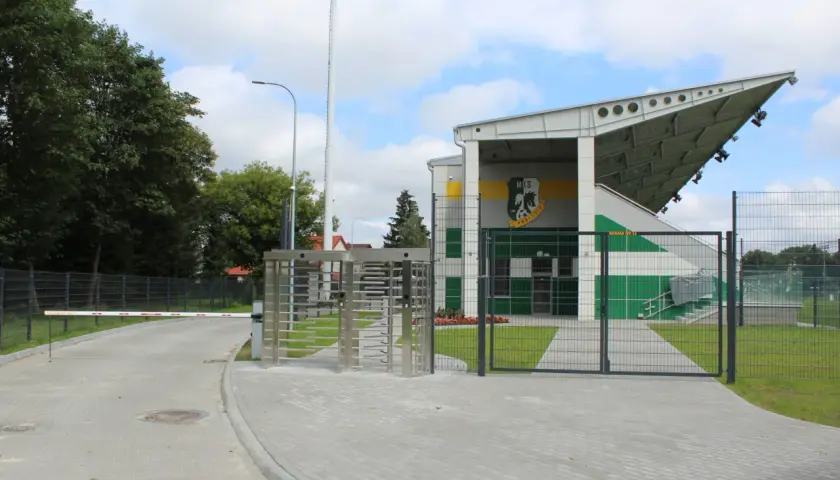 Nowoczesny stadion w Białej Podlaskiej z trybunami, bramami i obrotowymi kołowrotkami.