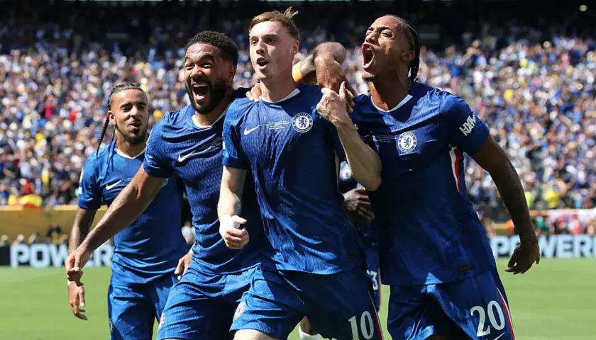 Radość zawodników Chelsea F.C. po zdobytej bramce. Piłkarze w niebieskich strojach świętują razem na boisku, otoczeni przez kibiców.
