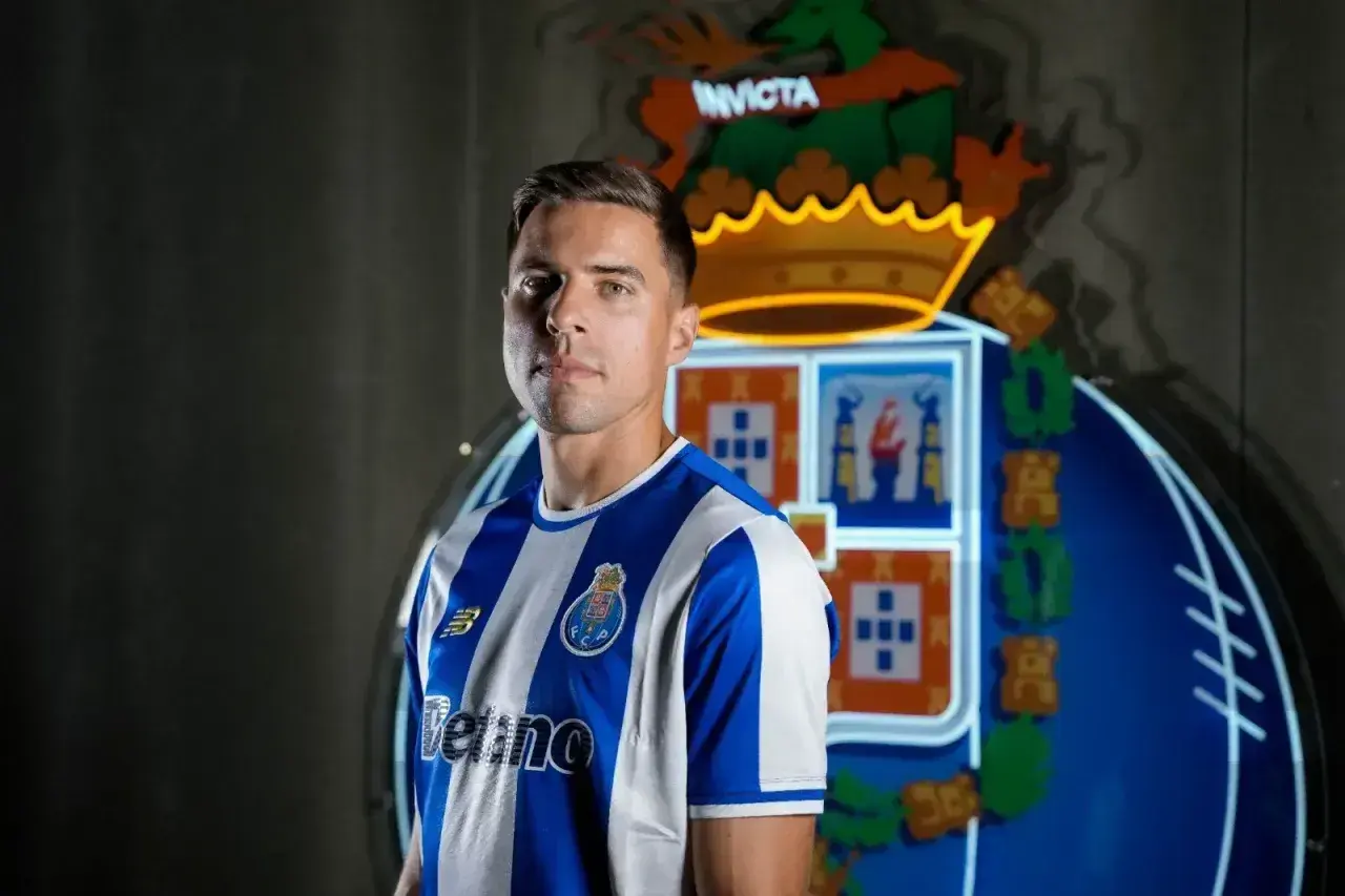 Piłkarz w koszulce FC Porto, gdzie gra Bednarek. Za nim neonowy herb klubu.