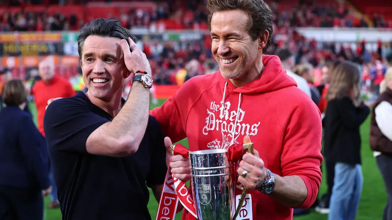 Ryan Reynolds i Rob McElhenney świętują sukces Wrexham A.F.C. z pucharem. Ich radość odzwierciedla pozytywne rankingi klubu.