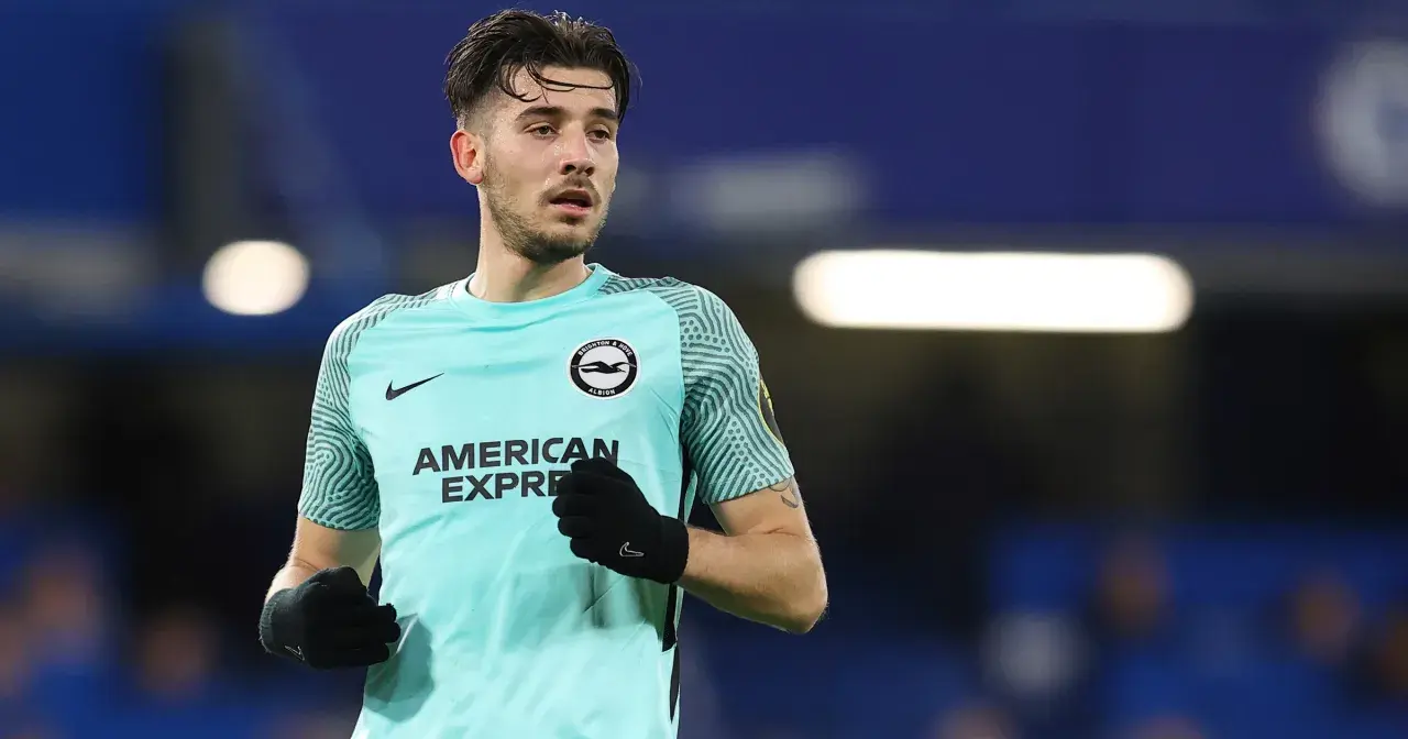 Piłkarz Jakub Moder w koszulce Brighton, zmagający się z kontuzją, na tle niebieskich trybun.