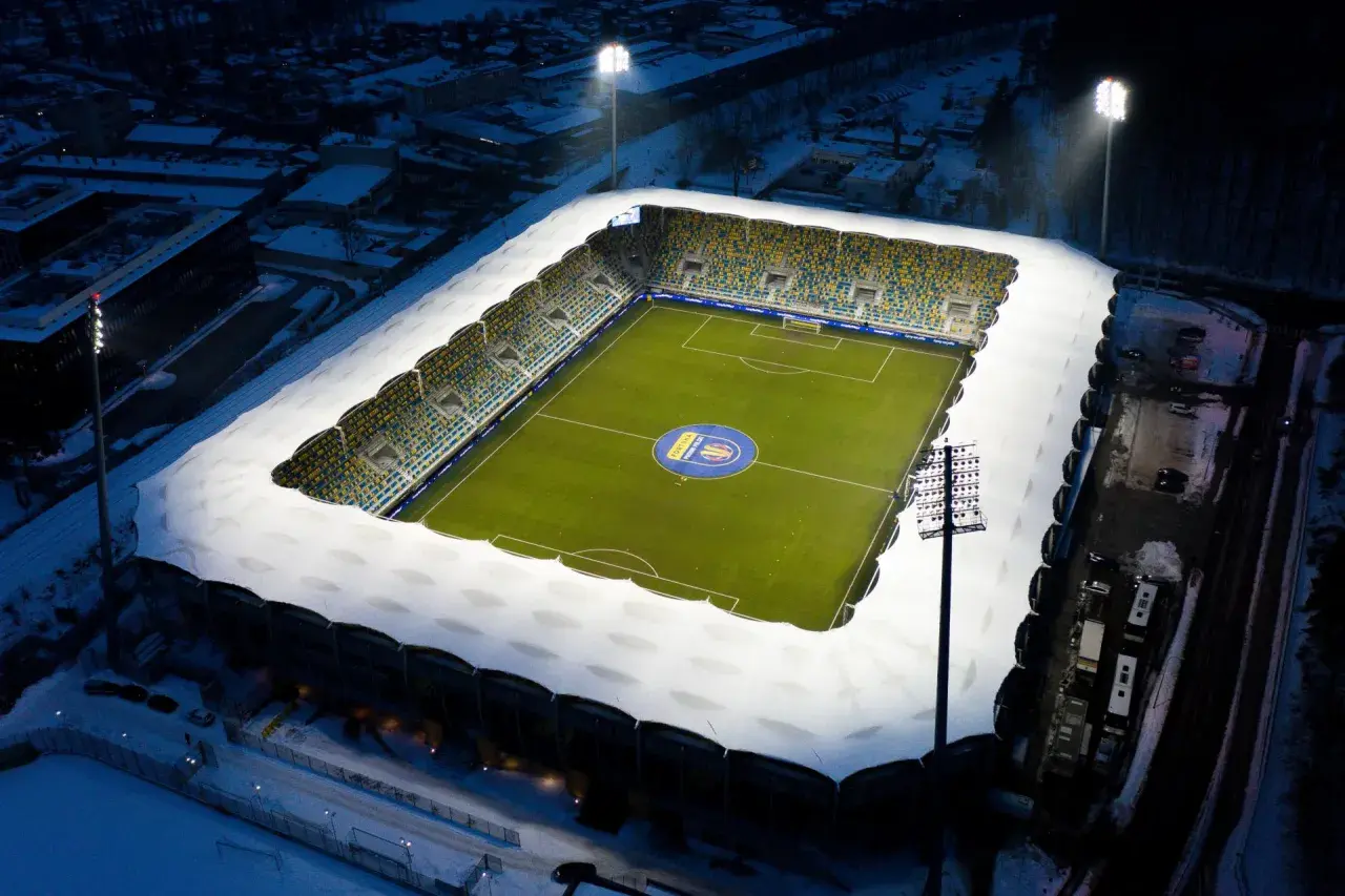 Zimowy wieczór na stadionie Gdynia Arka. Oświetlony stadion z zieloną murawą i śniegiem na trybunach, gotowy na mecz Bałtyk Gdynia.