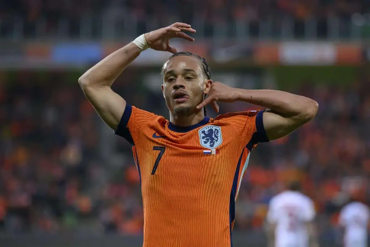Piłkarz Xavi Simons w pomarańczowej koszulce reprezentacji Holandii z numerem 7, z rękami przy głowie.