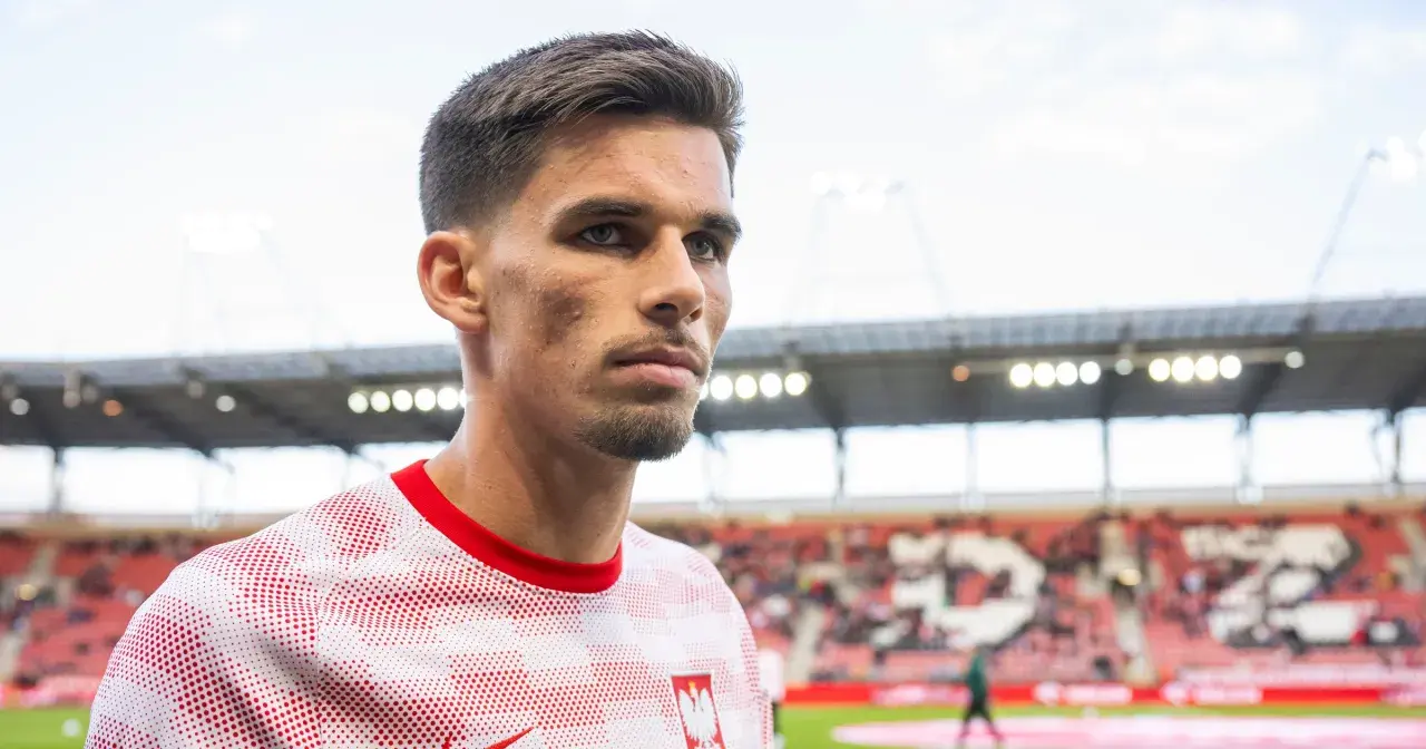 Filip Marchwiński w biało-czerwonej koszulce z godłem Polski, na tle stadionu.