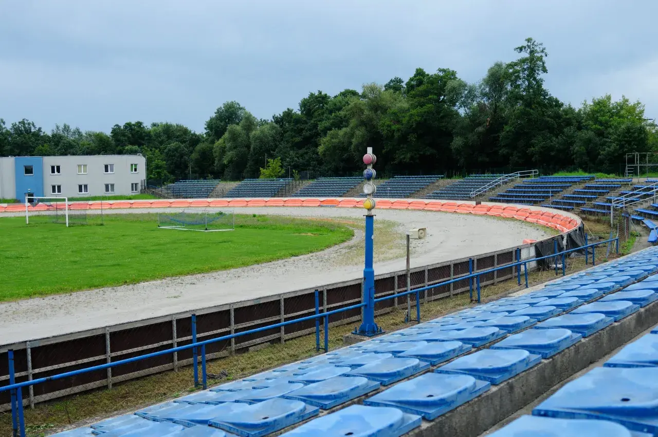Puste trybuny stadionu Wandy Kraków z widokiem na tor żużlowy i boisko.
