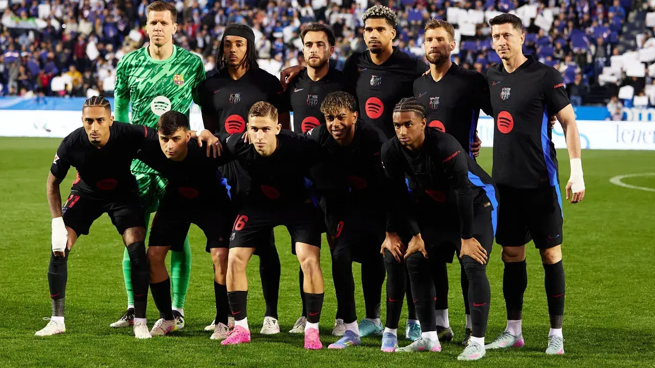 Drużyna FC Barcelona, znana z hiszpańskich zawodników, pozuje do zdjęcia w czarnych strojach.