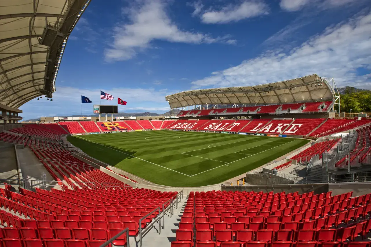 Puste trybuny stadionu Real Salt Lake, z zieloną murawą i niebieskim niebem.