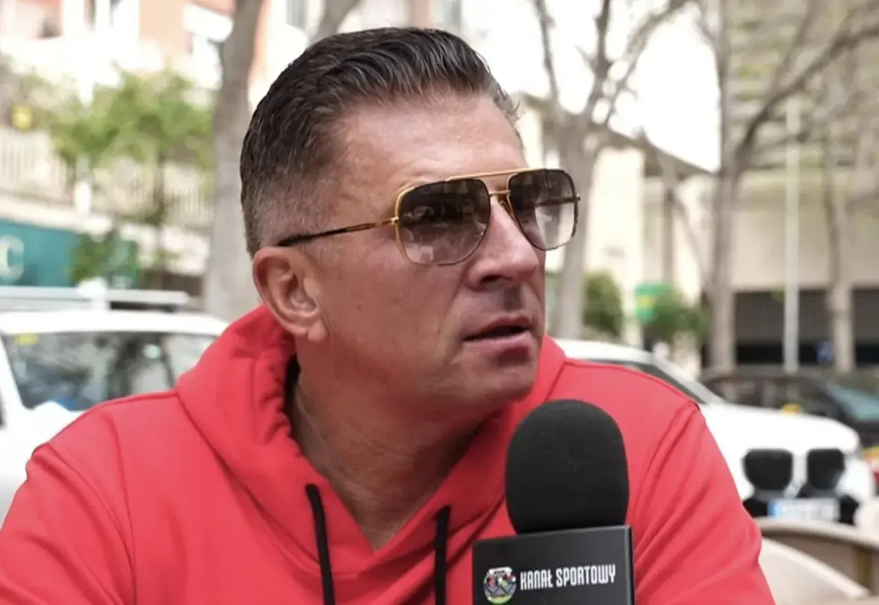 Mateusz Borek w czerwonej bluzie i okularach przeciwsłonecznych udziela wywiadu dla Kanału Sportowego, być może o Real Madryt.