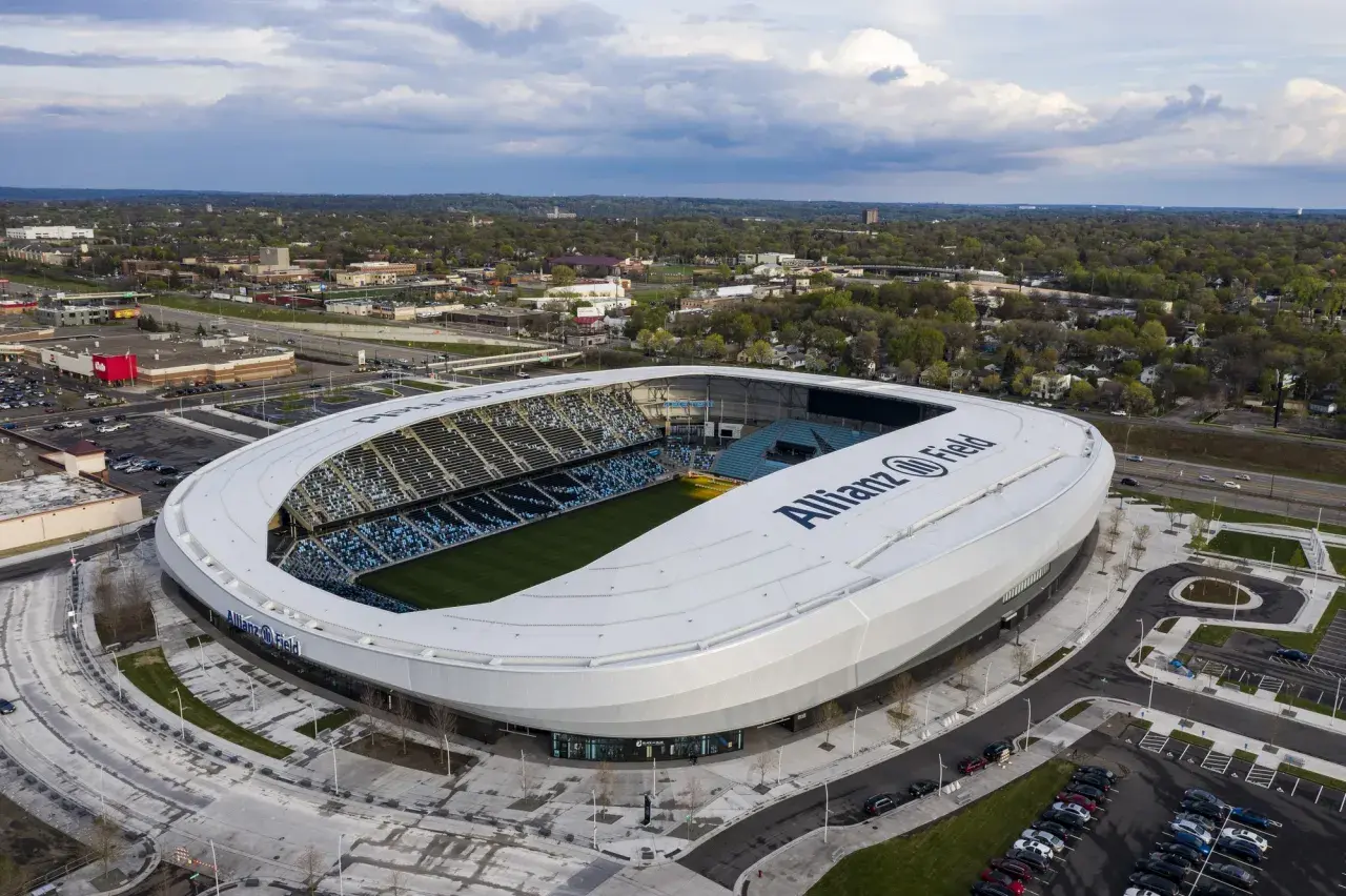 Widok z lotu ptaka na Allianz Field, nowoczesny stadion piłkarski, otoczony zielenią i parkingami.