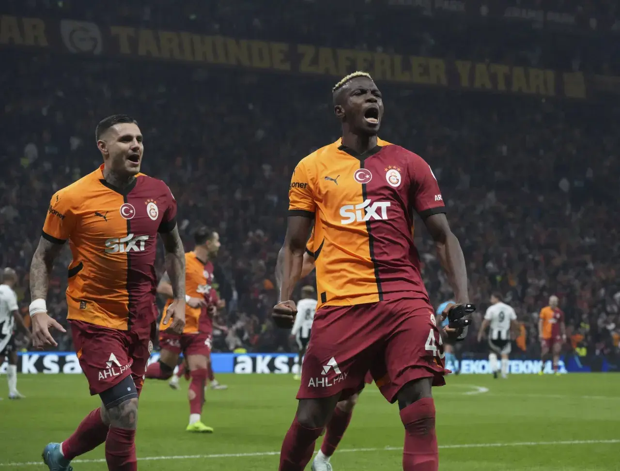 Dwóch zawodników Galatasaray świętuje zwycięstwo na boisku.