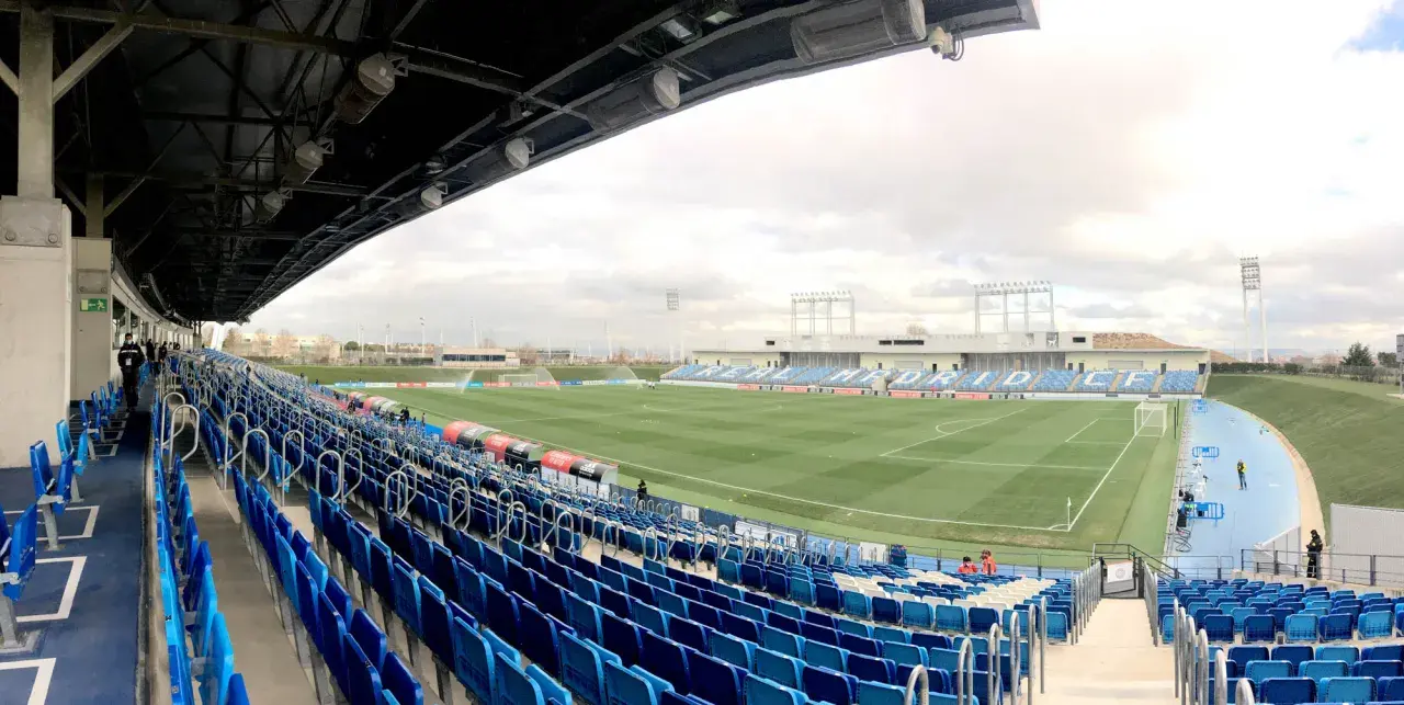 Puste trybuny stadionu Alfredo Di Stéfano, z zieloną murawą i niebieskimi siedzeniami, czekają na kibiców.
