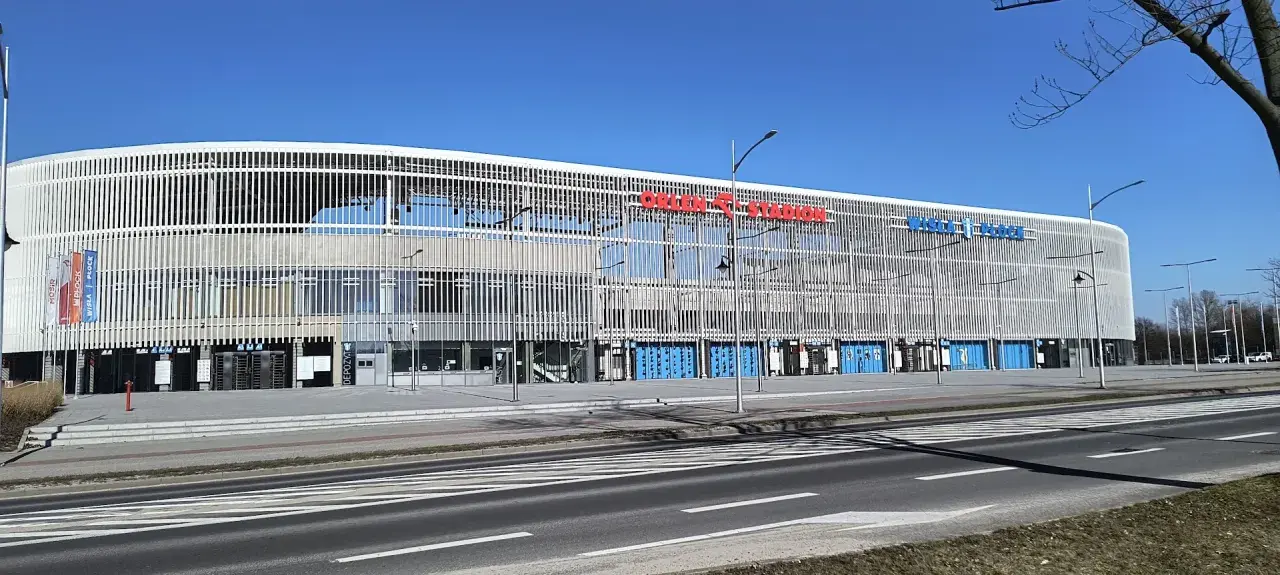 Nowoczesny stadion im. Kazimierza Górskiego w Płocku, z charakterystyczną, ażurową fasadą i niebieskimi bramami.