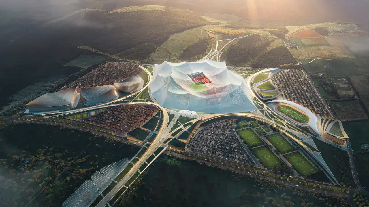 Futurystyczny kompleks sportowy z centralnym, zadaszonym stadionem, otoczony boiskami treningowymi i parkingami. Wygląda jak najwyżej położony stadion na świecie.