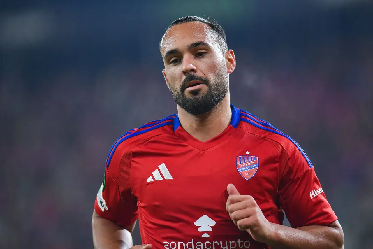 Piłkarz Ivi Lopez w czerwonej koszulce RKS Raków Częstochowa, z widocznym logo klubu i Adidasem. Mimo kontuzji, widać determinację na jego twarzy.