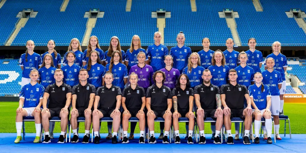 Drużyna piłkarska Lech Poznań UAM w komplecie, gotowa do gry na stadionie.