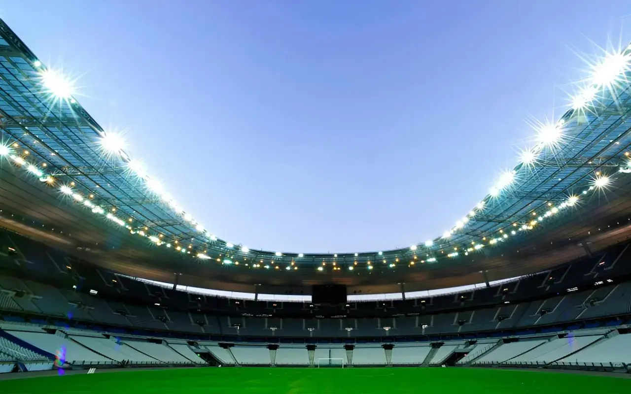 Puste trybuny Stade de France czekają na kibiców. Jasne światła oświetlają zieloną murawę.