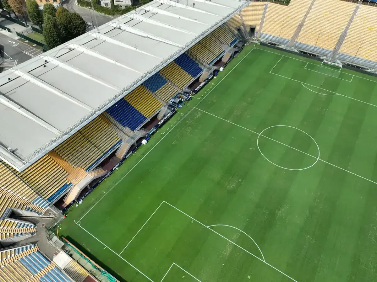 Puste trybuny stadionu Ennio Tardini, z zieloną murawą i białymi liniami boiska.