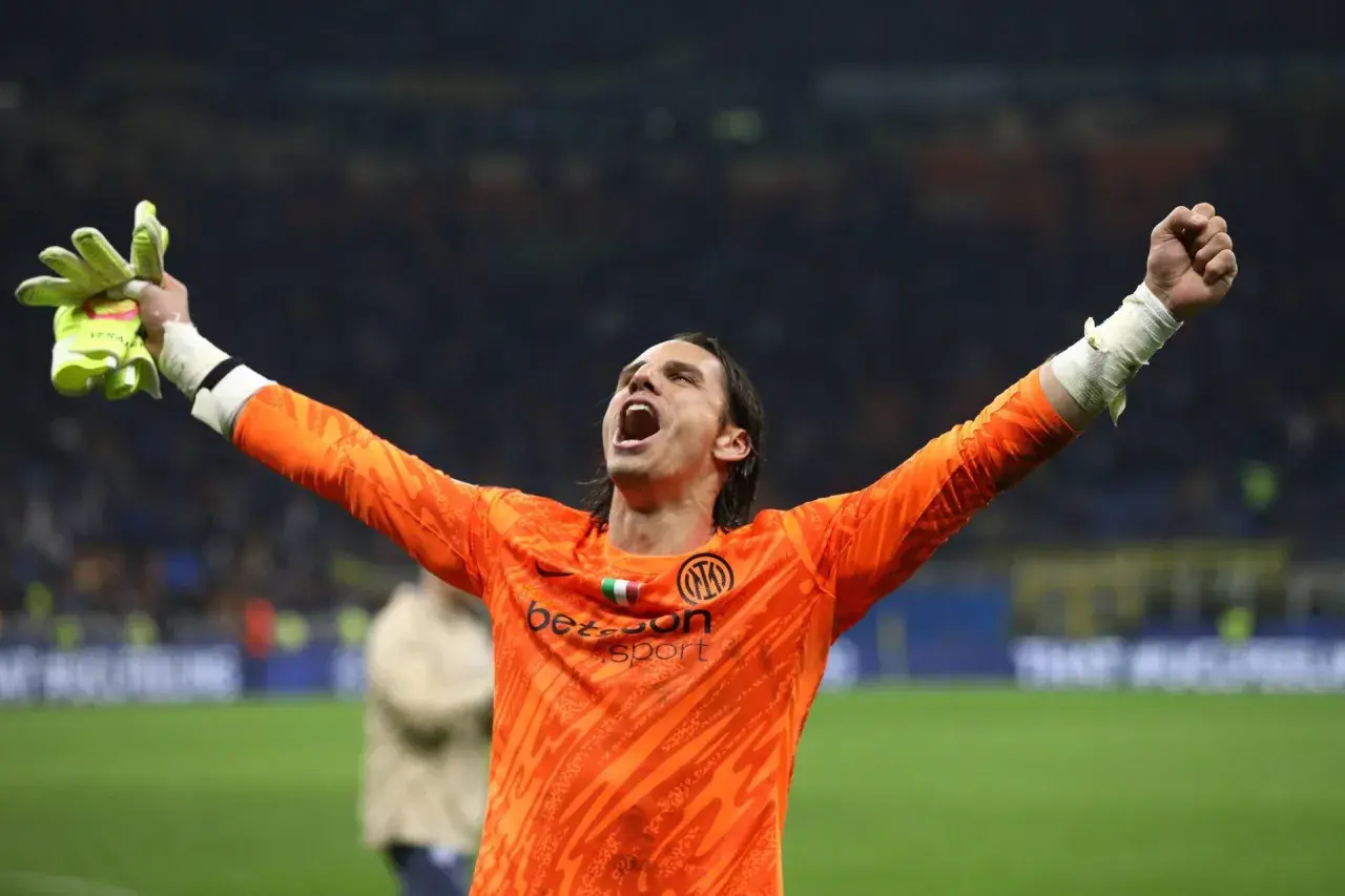Bramkarz Yann Sommer w pomarańczowej koszulce z podniesionymi rękami świętuje zwycięstwo.