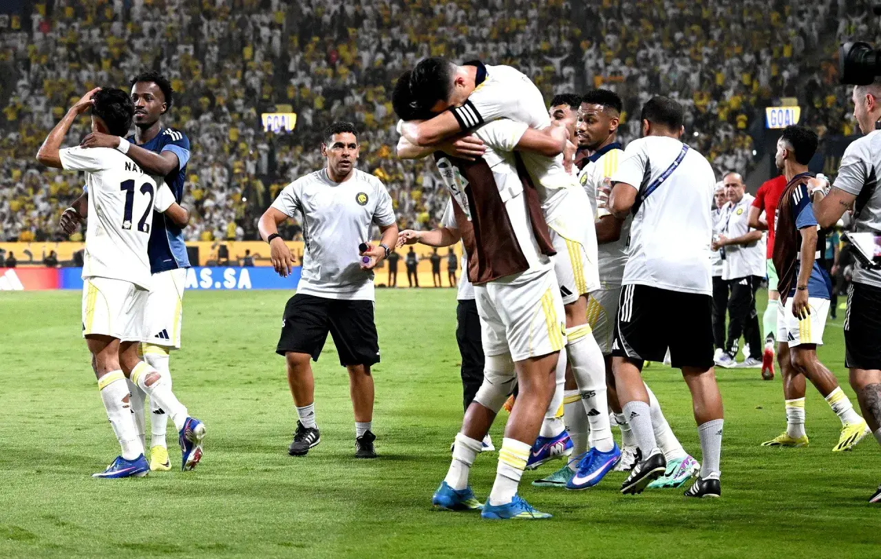 Piłkarze świętują zwycięstwo, przytulając się na boisku. W tle tłum kibiców, którzy przyszli zobaczyć, kiedy gra Ronaldo.