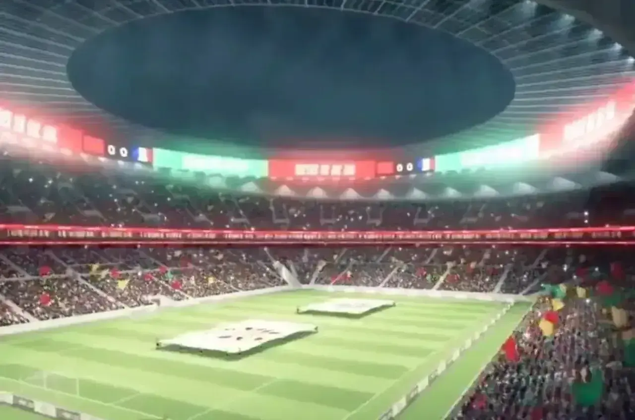 Widok na pełen kibiców, oświetlony stadion, gdzie trwa mecz. W tle widać tablicę wyników, a trybuny ozdobione są flagami. To z pewnością najładniejszy stadion na świecie!