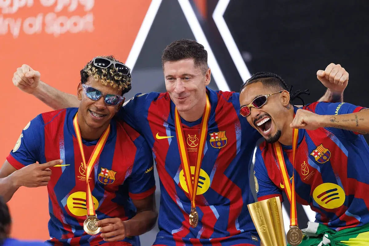 Trzej zawodnicy FC Barcelony w okularach przeciwsłonecznych świętują zdobycie Superpucharu Hiszpanii.