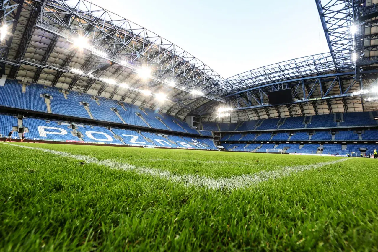 Zielona murawa i niebieskie trybuny stadionu Lecha Poznań, gotowe na kolejny mecz.