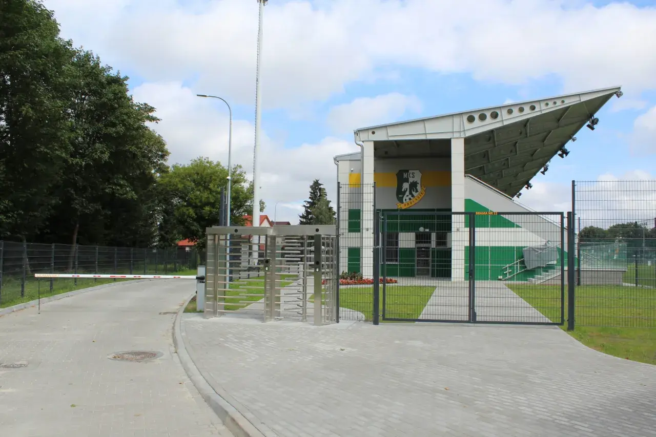 Nowoczesny stadion w Białej Podlaskiej z trybunami, bramami i obrotowymi kołowrotkami.