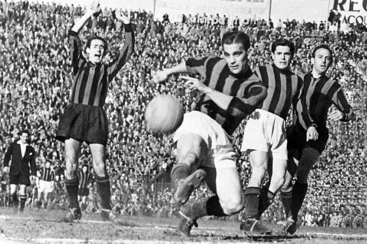 A.C. Milan – zawodnicy w akcji. Piłkarze w pasiatych koszulkach walczą o piłkę na tle trybun pełnych kibiców.
