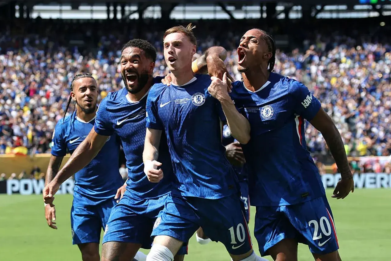 Radość zawodników Chelsea F.C. po zdobytej bramce. Piłkarze w niebieskich strojach świętują razem na boisku, otoczeni przez kibiców.