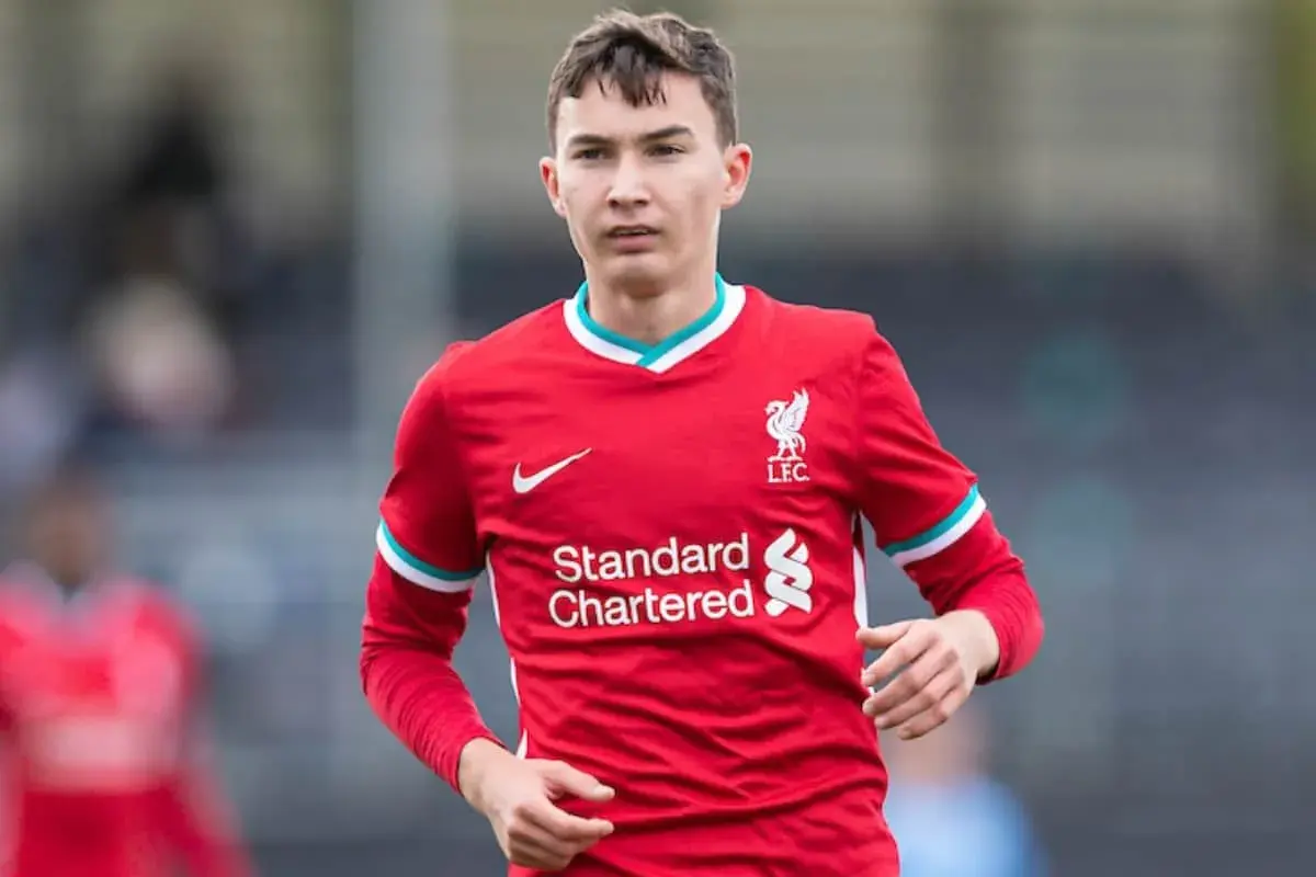 Młody piłkarz Mateusz Musiałowski w czerwonej koszulce Liverpoolu, z dumą nosi herb klubu.