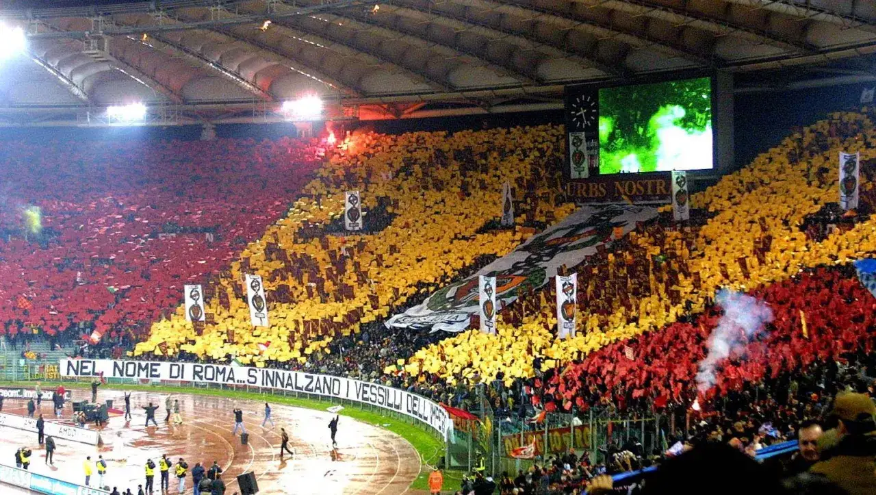 Trybuna stadionu AS Roma wypełniona kibicami w czerwonych i żółtych barwach, tworząc spektakularną oprawę.