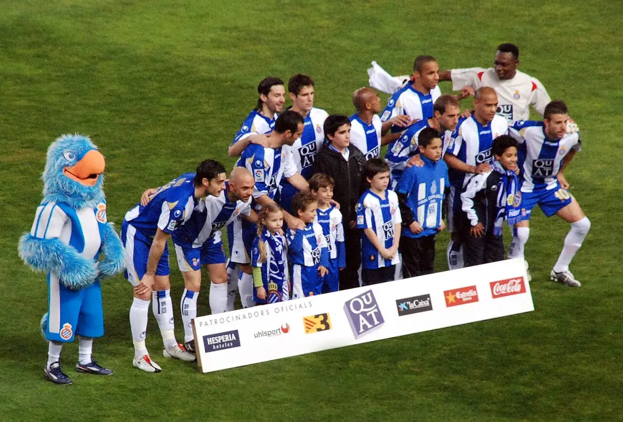 Drużyna Espanyol – zawodnicy i maskotka pozują do zdjęcia na boisku.