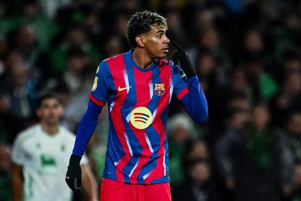 Młody Lamine Yamal w koszulce FC Barcelona, z charakterystycznym wzorem, gestykuluje na boisku.