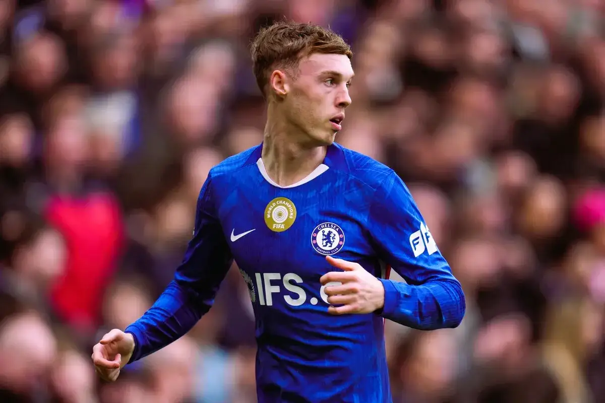 Młody piłkarz Cole Palmer w niebieskiej koszulce Chelsea, z dumą prezentuje swoje osiągnięcia na boisku.
