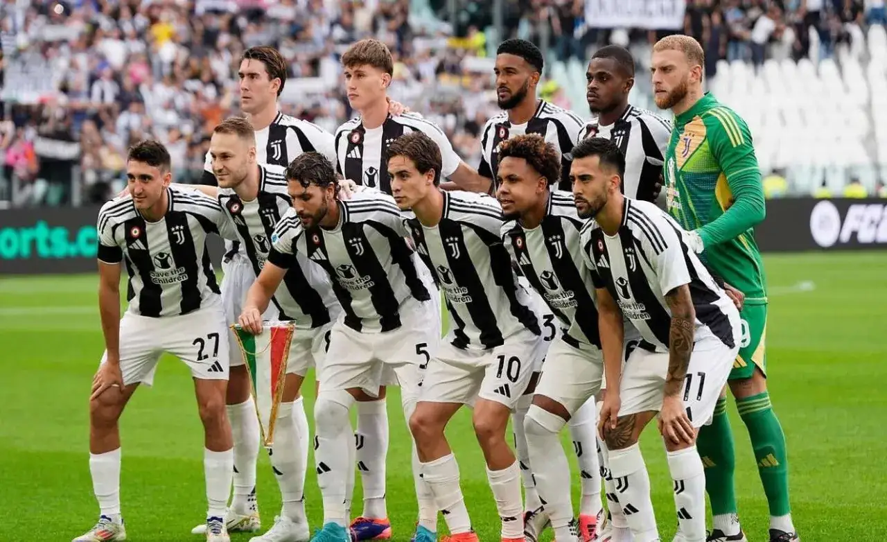 Juventus – zawodnicy w czarno-białych strojach pozują do zdjęcia na boisku. W tle trybuny pełne kibiców.