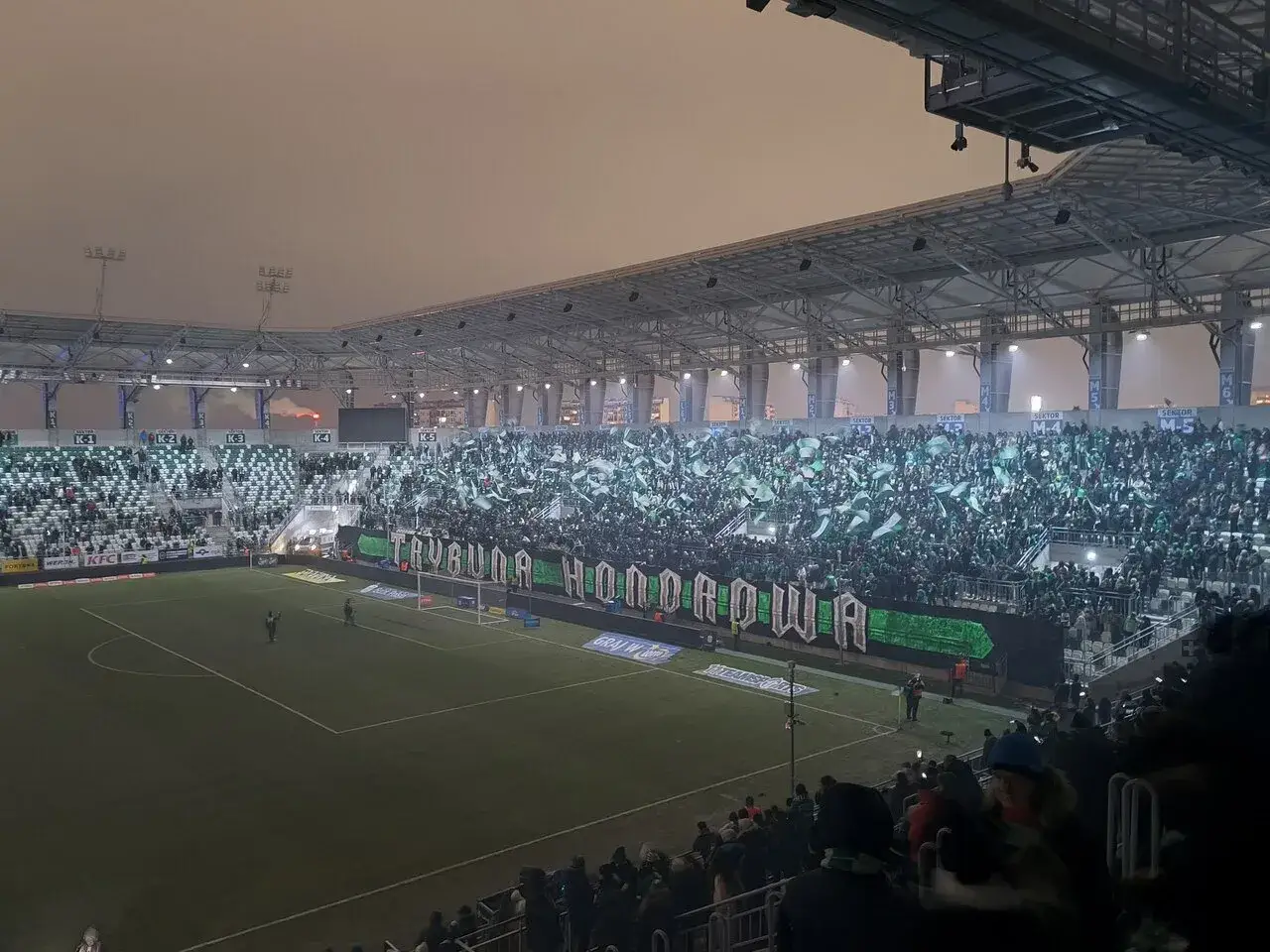 Trybuna honorowa kibicuje Radomiakowi Radom. Tysiące zielonych flag faluje na trybunach stadionu.