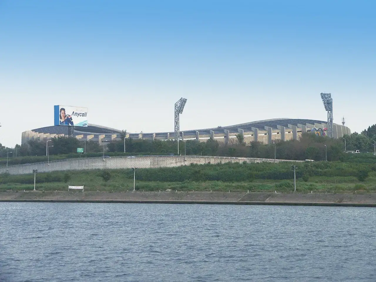 Stadion seul world cup, z widoczną reklamą Anycall i masztami oświetleniowymi, nad spokojną rzeką.