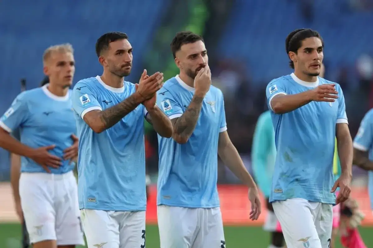Piłkarze Lazio w jasnoniebieskich strojach, po meczu z Udinese, klaszczą i rozmawiają na boisku.