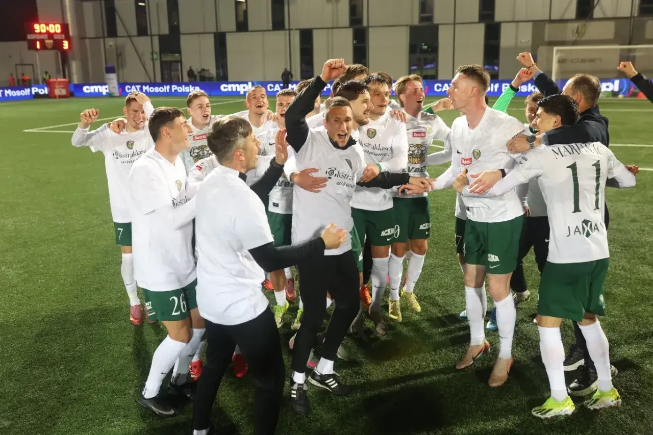 Piłkarze świętują awans do ekstraklasy. Radość i okrzyki na murawie po zwycięskim meczu.