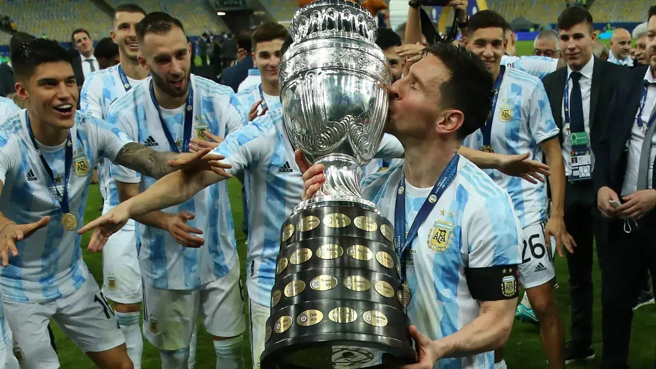 Lionel Messi całuje puchar Copa América, świętując zwycięstwo z drużyną Argentyny. Copa América odbywa się co kilka lat, przynosząc emocje fanom piłki nożnej.