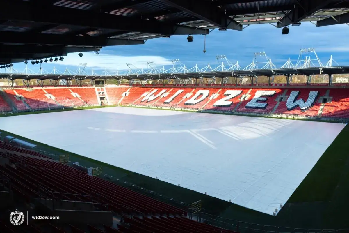 Stadion Widzewa przygotowany do rozbudowy. Boisko przykryte białym materiałem, na trybunach widnieje napis 