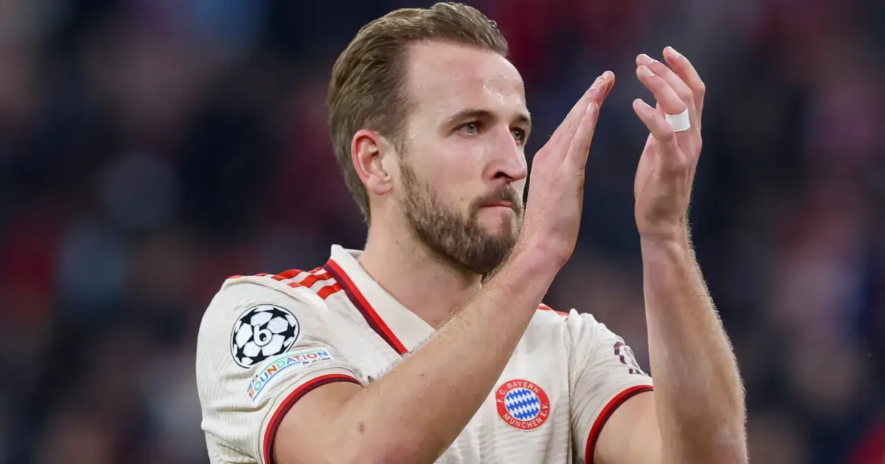 Harry Kane w białej koszulce Bayernu Monachium, z opaską na palcu, klaszcze podczas meczu.
